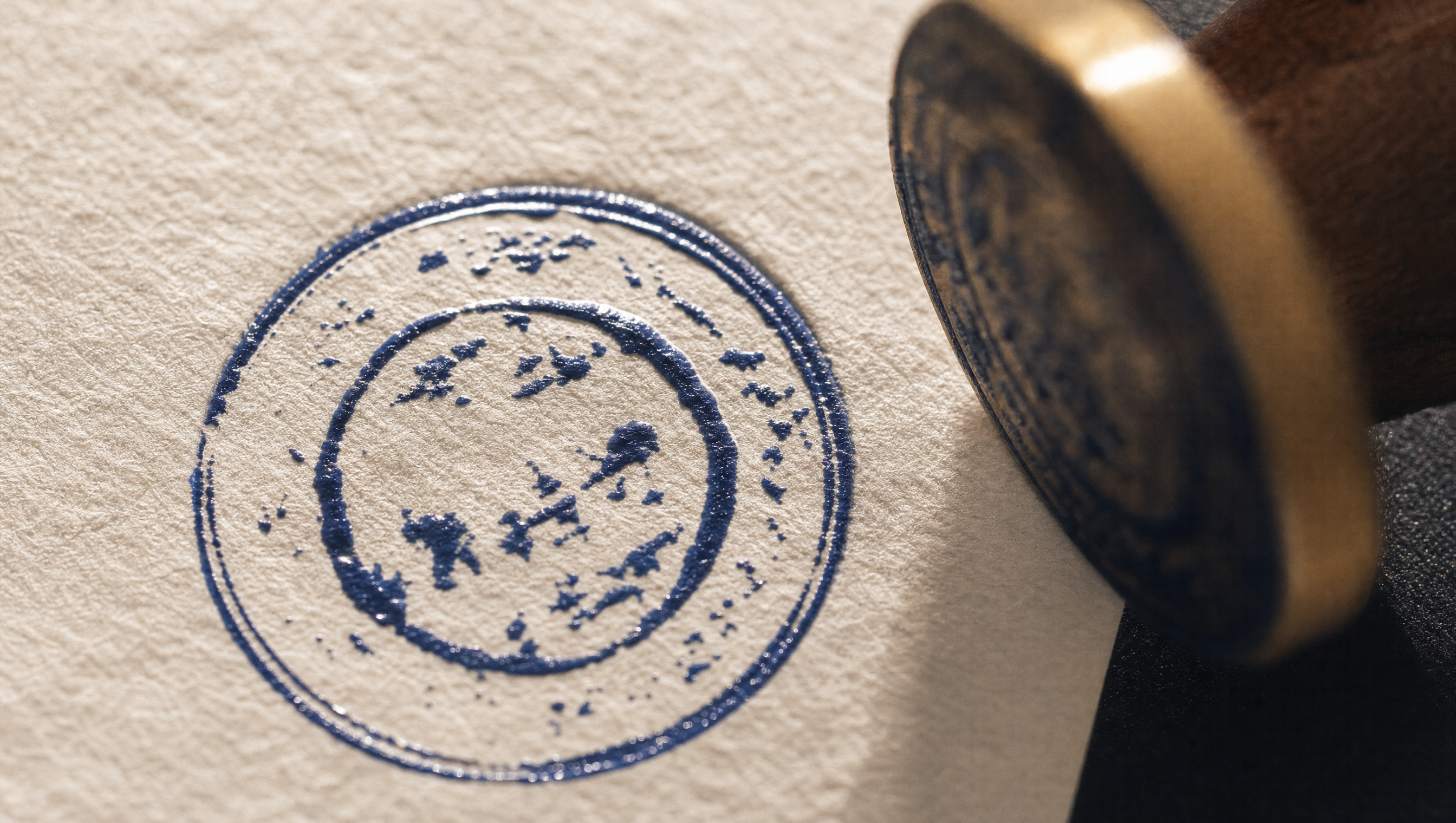 Macro photograph of the Intention Inbox postmark pressed into warm cream paper in deep blue ink
